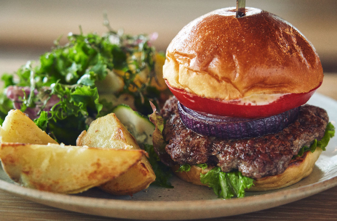 「オーストラリア産 グラスフェッドビーフのハンバーガー ローストポテトと自家製のピクルス」(1,500円、税込)。サラダやポテトもしっかりついて、プレート料理としても完成している。